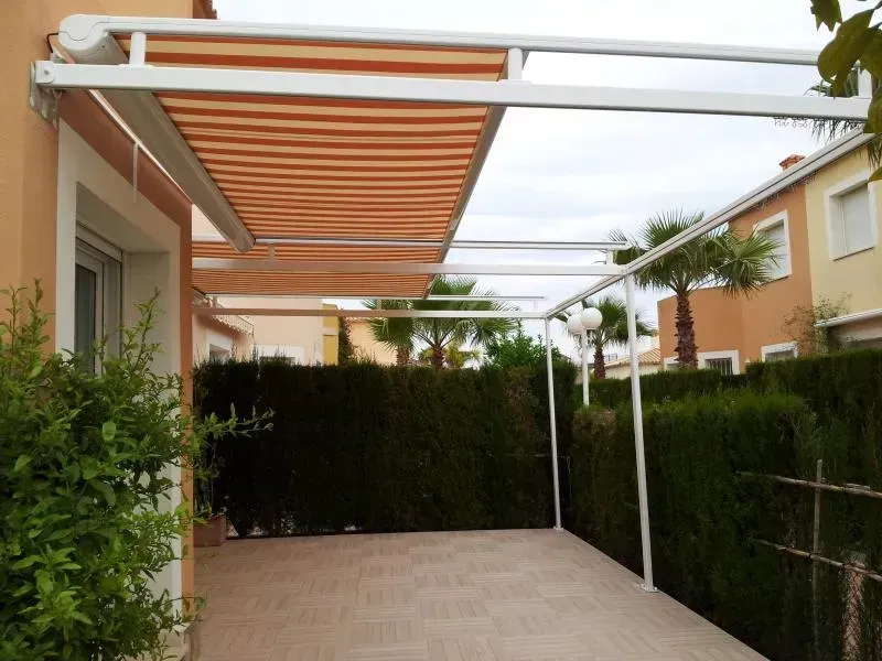 Un patio con un dosel encima y palmeras al fondo.