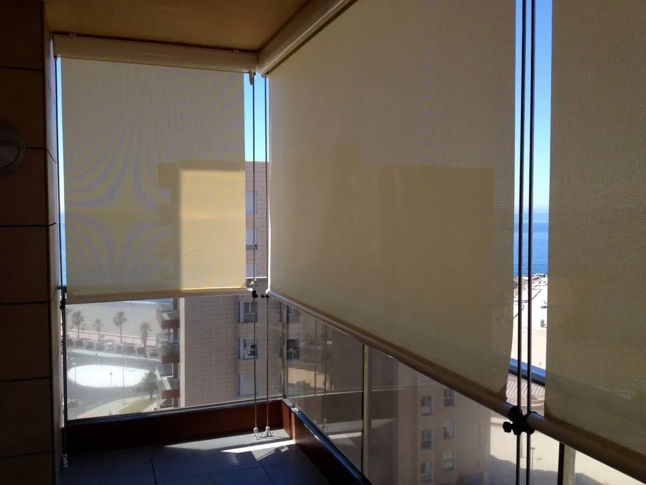 Un balcón con persianas en las ventanas y vista al mar.