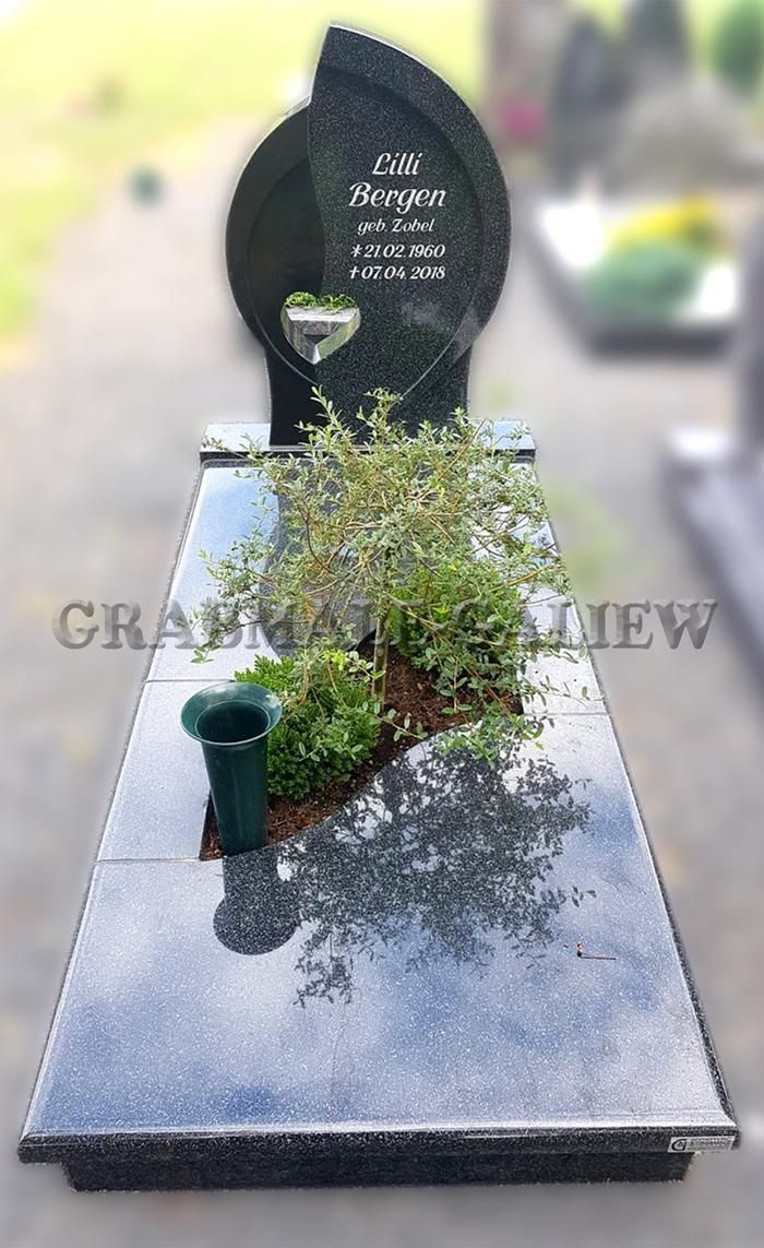 Ein Grab mit einer Vase mit Pflanzen darauf auf einem Friedhof.