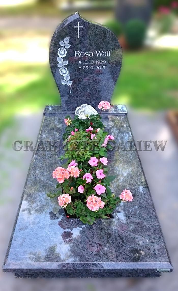 Ein Grabstein mit rosa Blumen darauf auf einem Friedhof.