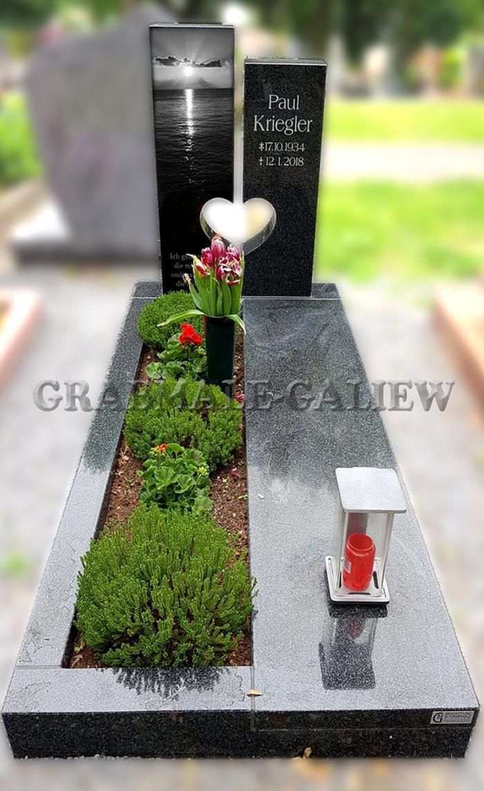 Ein Grab mit Blumen und einer Laterne darauf auf einem Friedhof.