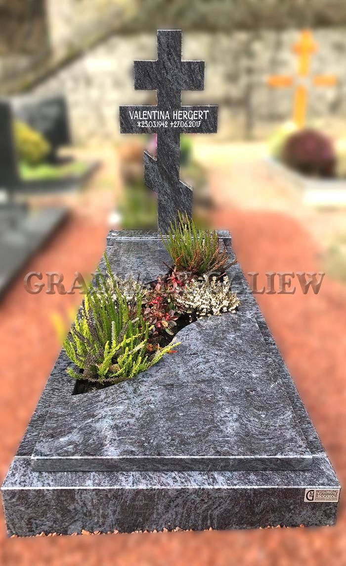 Ein Grab mit einem Kreuz darauf auf einem Friedhof.