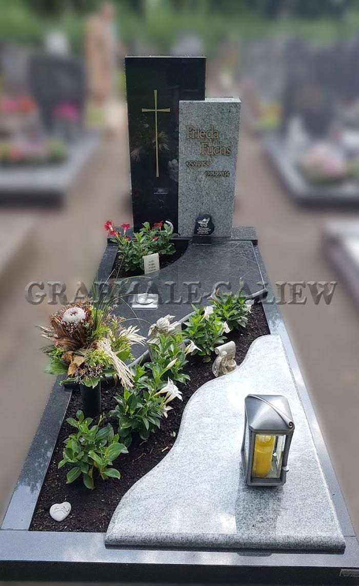 Ein Grab mit einer Laterne und Blumen darauf auf einem Friedhof.