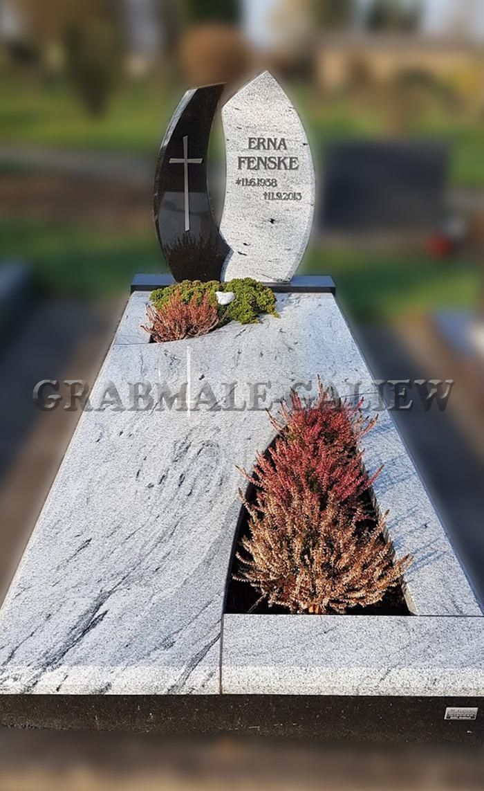 Ein Grabstein mit einem Kreuz und Blumen auf einem Friedhof.