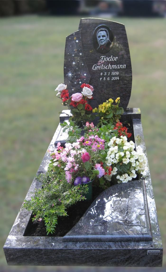 Ein Grab mit Blumen und einem Bild eines Mannes darauf