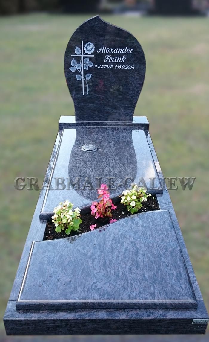 Ein Grab mit Blumen darin und einem Kreuz darauf