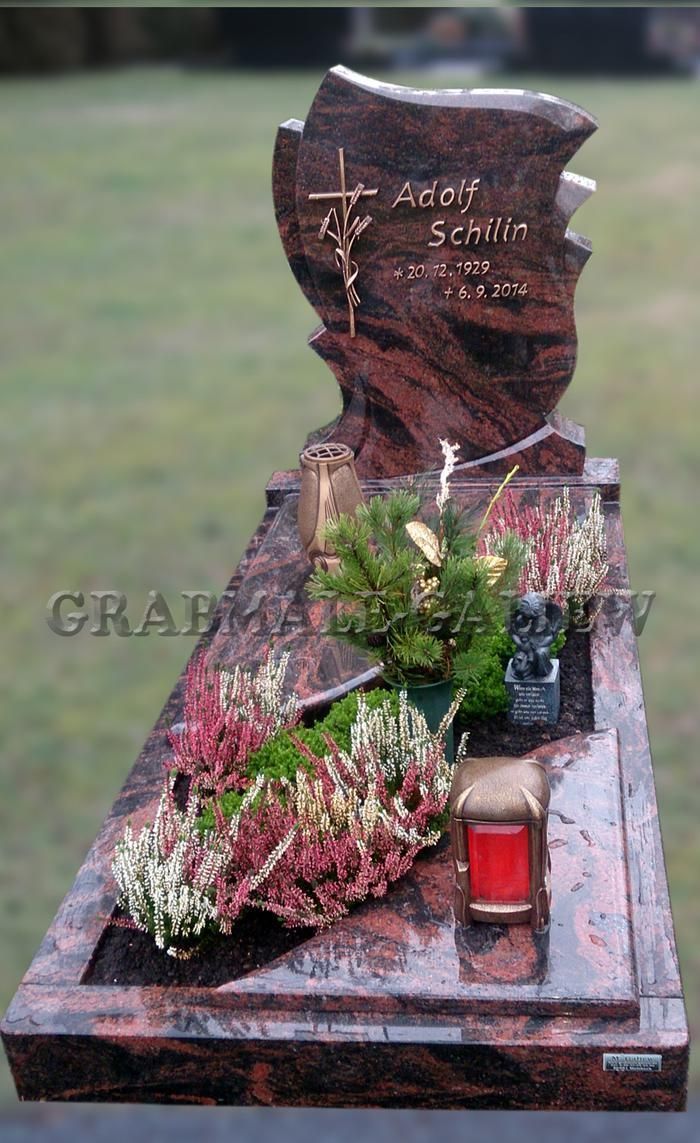 Ein Grab mit Blumen und einer roten Kerze darauf