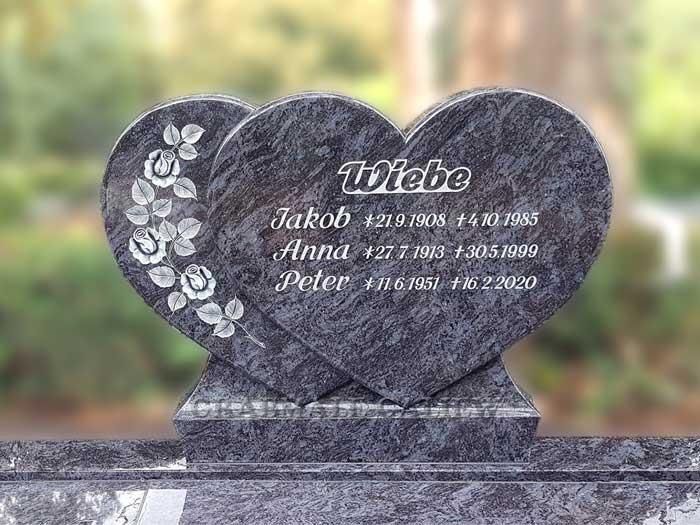 Ein Grabstein in Herzform mit Blumen darauf.