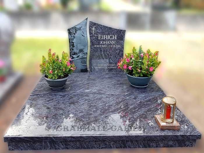 Ein Grab mit Blumen und einer Kerze darauf auf einem Friedhof.