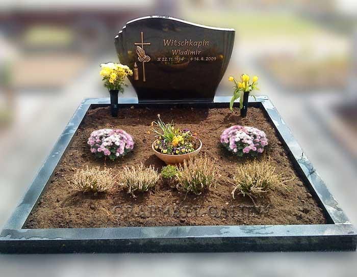 Ein Grab mit Blumen und einem Kreuz darauf