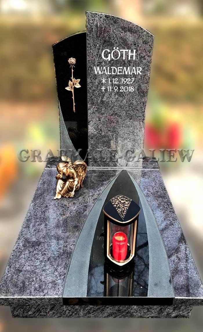 Ein Grabstein mit einer Laterne und einem Kreuz darauf.