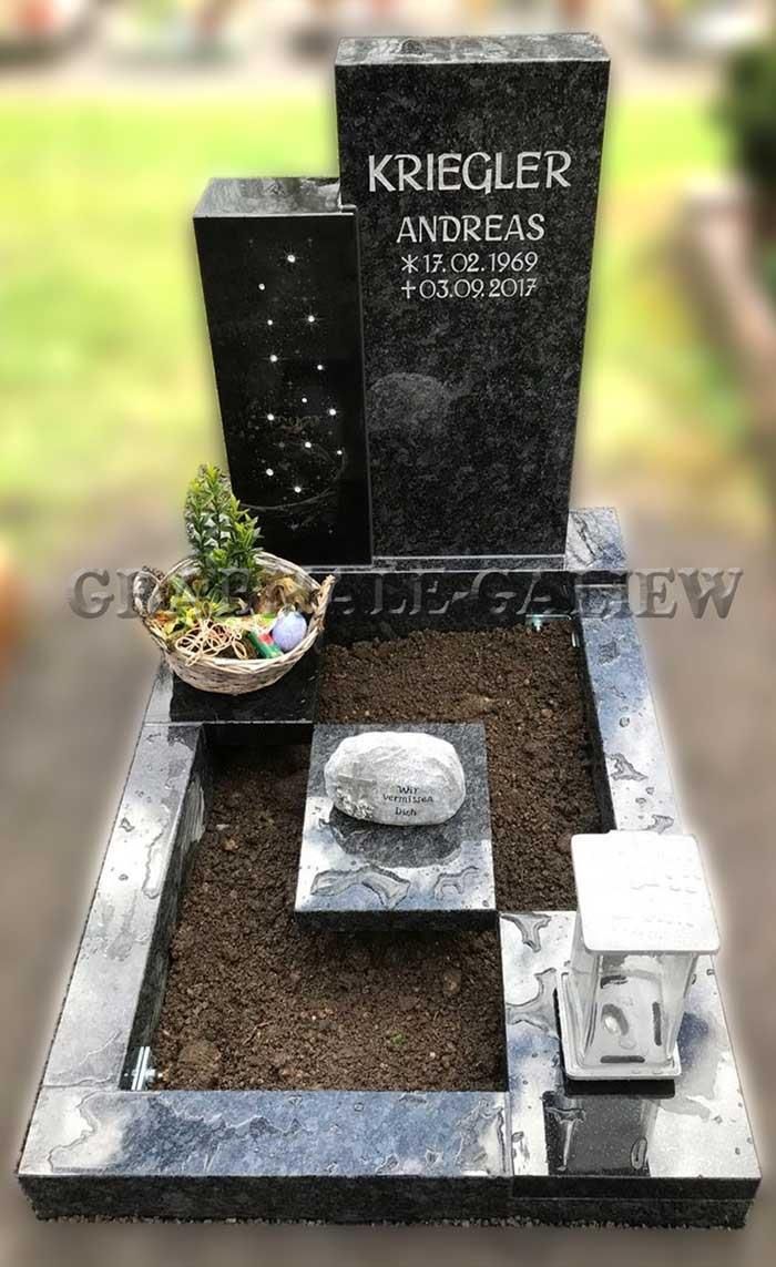 Ein schwarzer Grabstein mit einer Pflanze in einem Korb darauf.