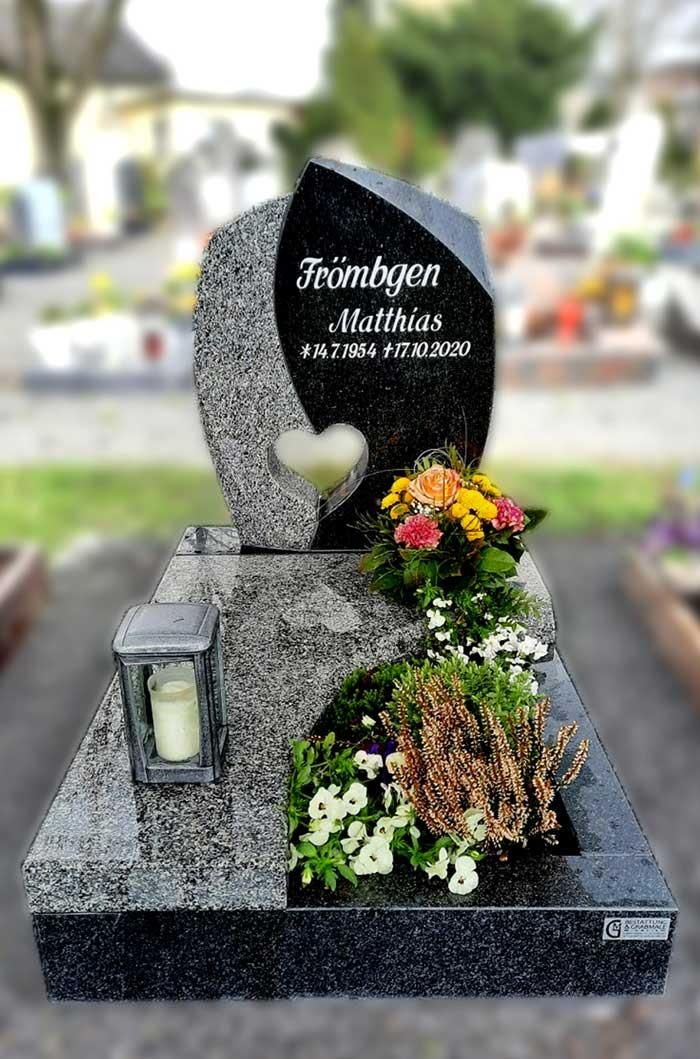 Ein Grabstein mit Blumen und einer Laterne auf einem Friedhof.