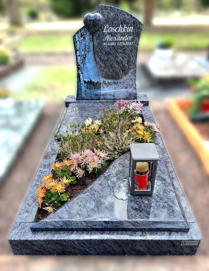 Ein Grab mit Blumen und einer Kerze darauf auf einem Friedhof.