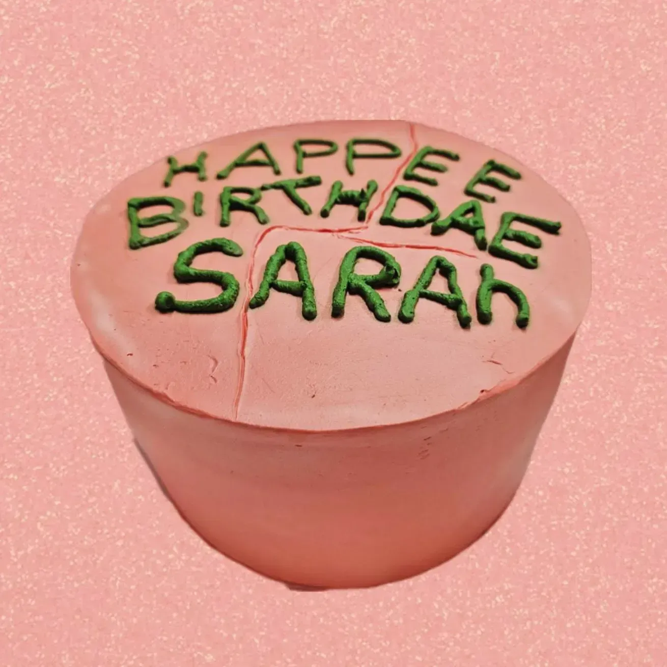 Tarta de cumpleaños rosa con glaseado verde que dice