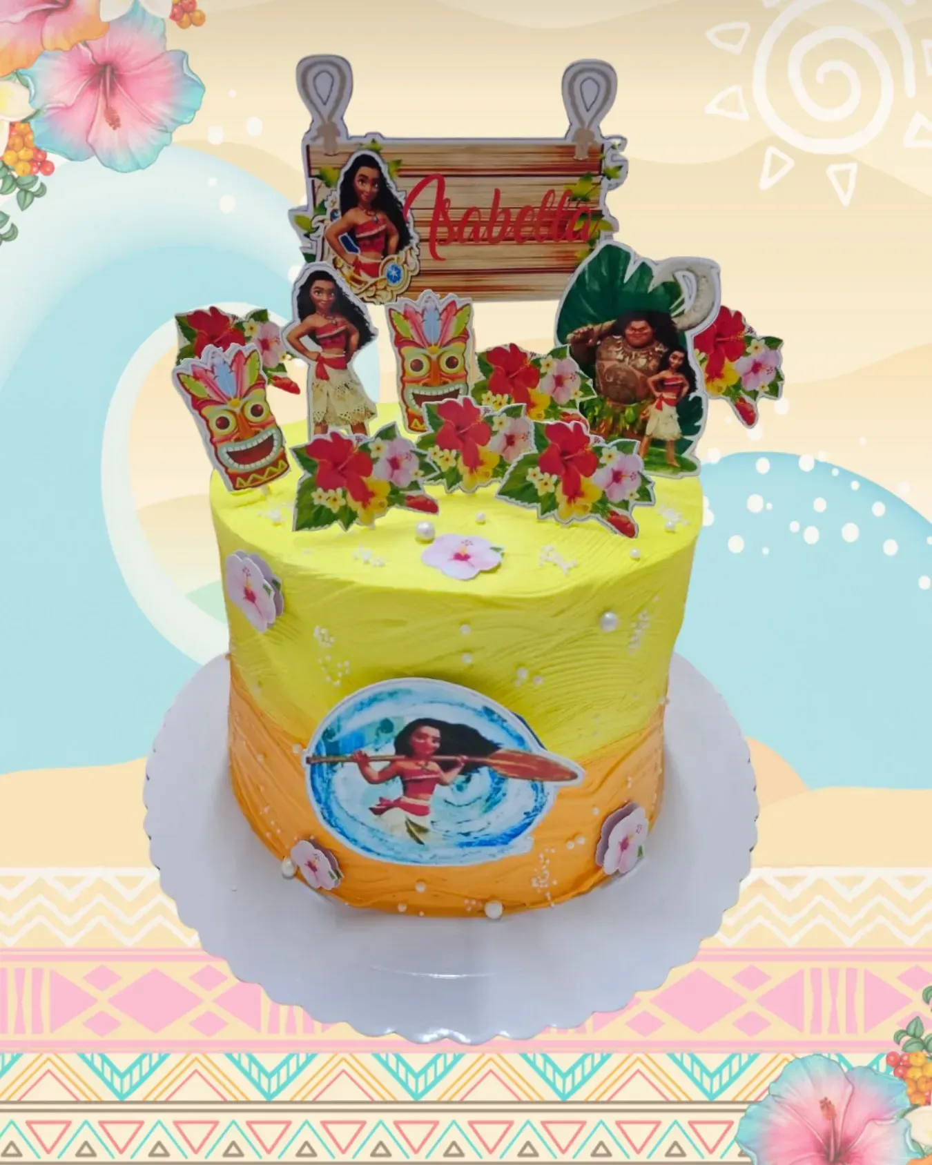 Tarta temática de Moana con figuras de los personajes y cartel con el nombre, decorada con glaseado amarillo y naranja y flores de hibisco.