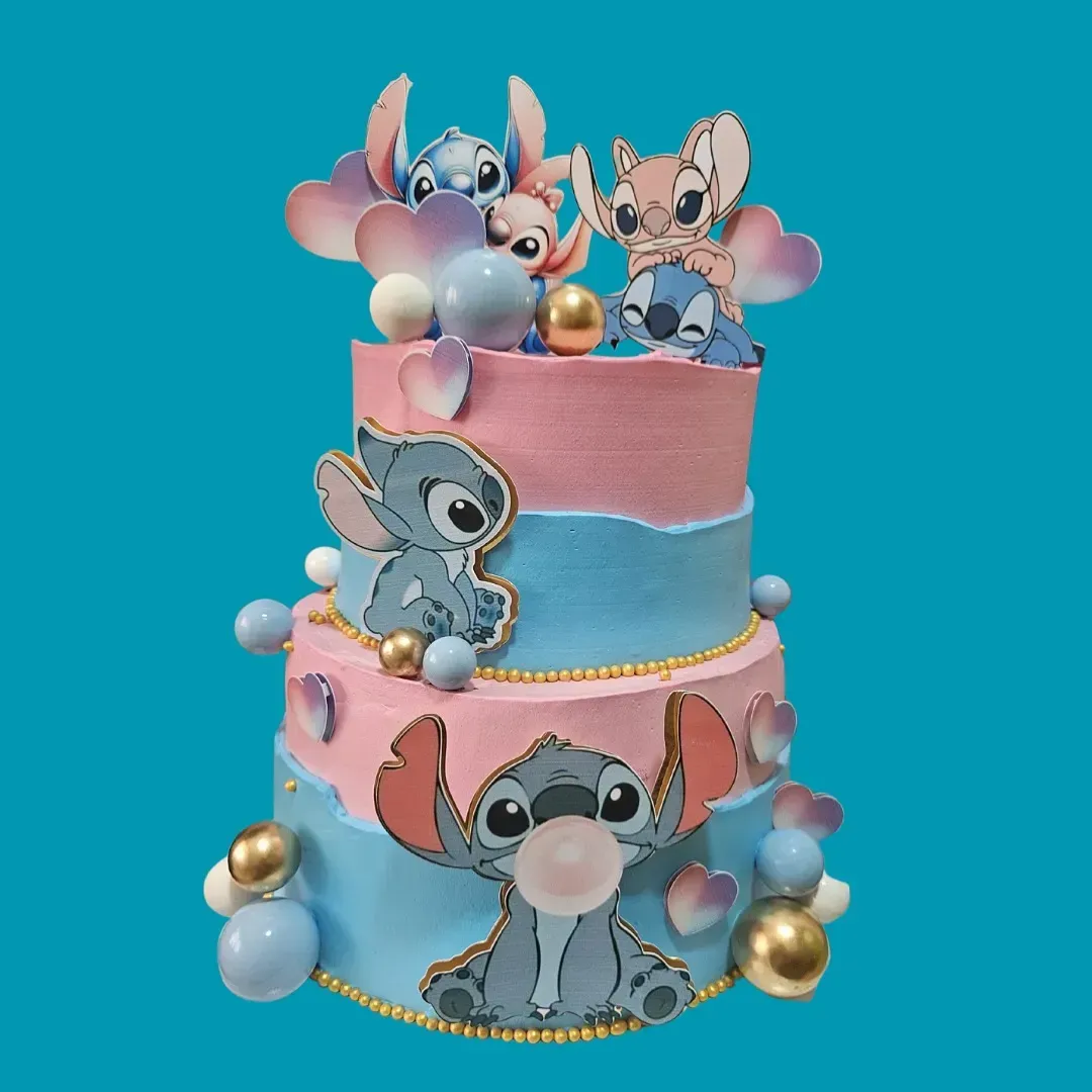 Tarta de tres pisos con decoración de Stitch y un ángel, glaseado rosa y azul, detalles dorados y azules.