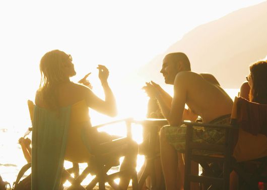 Silhouetted people chatting at an outdoor café in warm sunset light