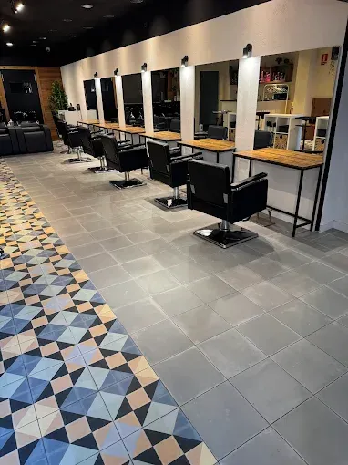 Interior de peluquería con estaciones de peinado y suelo estampado.