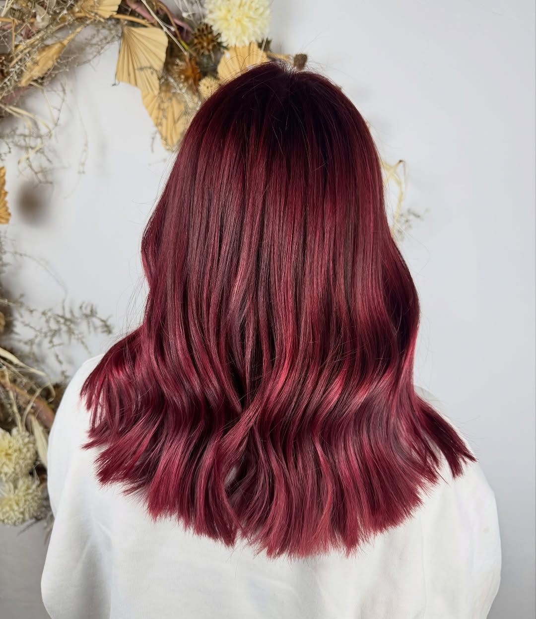 Mujer con cabello ondulado de color burdeos intenso.
