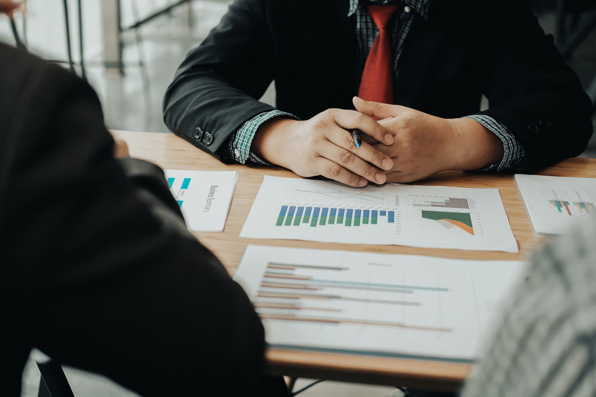 Reunión de negocios con las manos entrelazadas sobre gráficos y tablas.