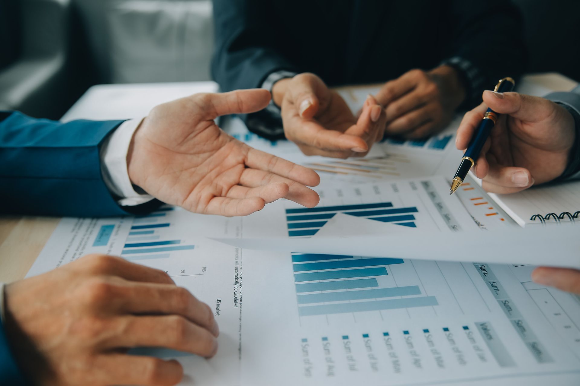 Manos señalando gráficos financieros durante una reunión.