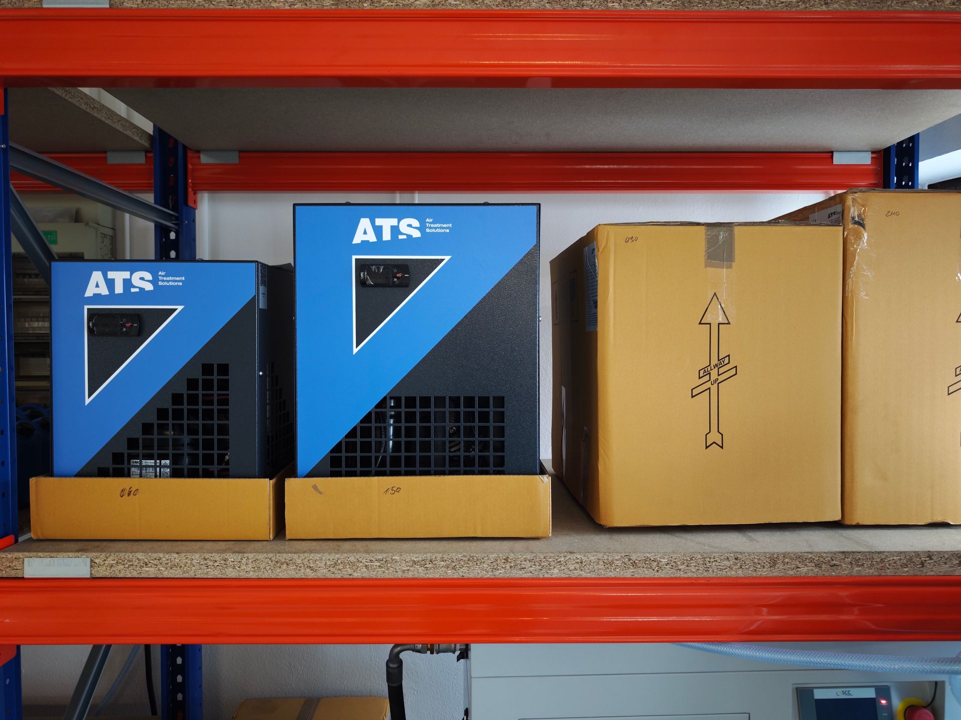 Zwei blaue und schwarze ATS-Lufttrockner auf einem Regal neben Pappkartons.