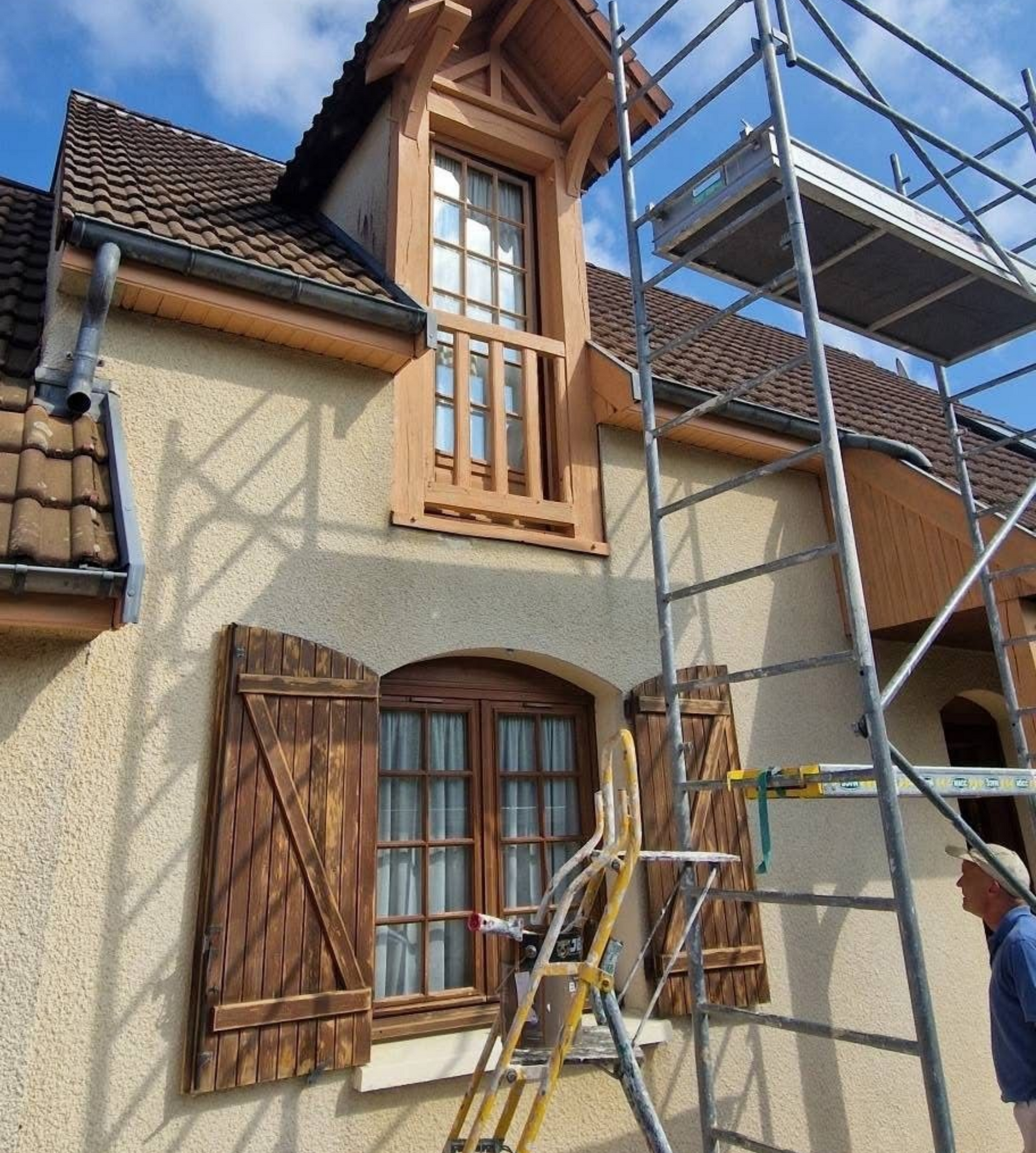 Façade de la maison en rénovation, avec des échafaudages et un ouvrier.