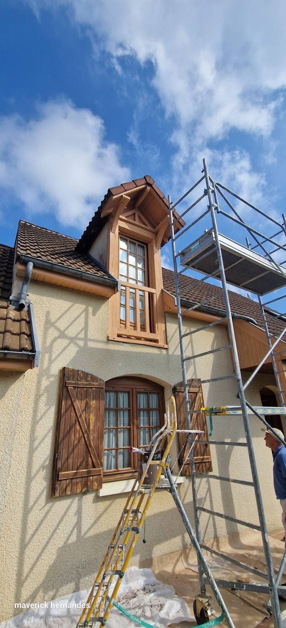 Extérieur de la maison avec échafaudages et échelles pendant la réparation du toit.
