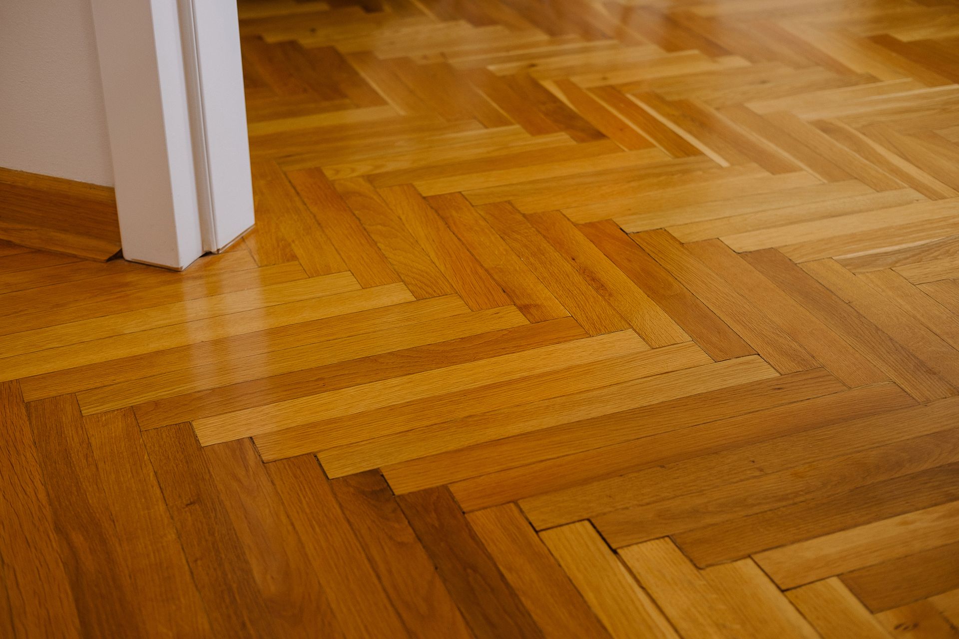 Sol en parquet dans un couloir avec une porte à gauche.