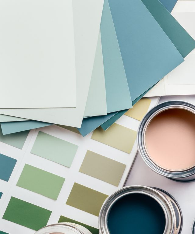 Nuanciers et échantillons de peinture dans des tons doux bleus, vert pâle et crème, avec deux pots de peinture ouverts.