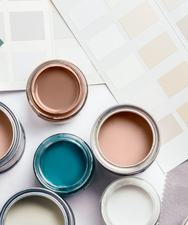 Des pots de peinture ouverts de couleur turquoise, beige, or rose et blanc sur une surface carrelée claire.