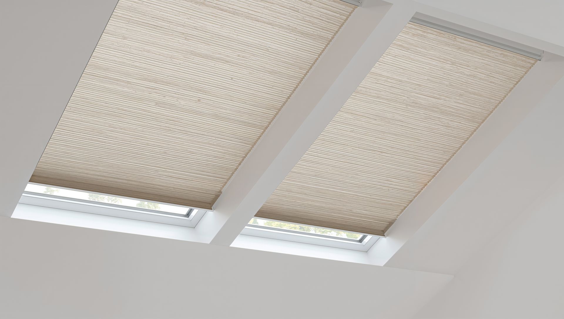 Deux stores beiges de puits de lumière, partiellement ouverts, laissent entrevoir la lumière en dessous, sur un plafond blanc incliné.