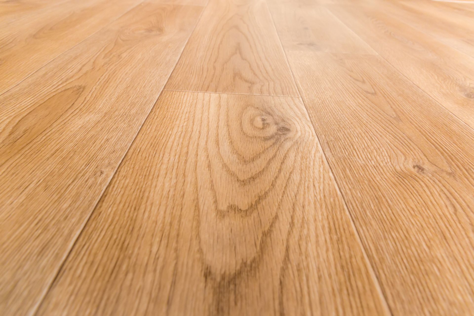 Gros plan sur un parquet en chêne clair laissant apparaître le veinage et les joints des lames.