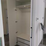 ein weißer Kleiderschrank mit Schubladen und Regalen in einem Zimmer.