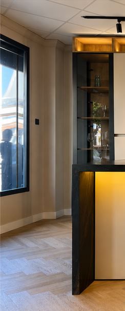 Interior moderno con una vitrina alta, iluminación indirecta cálida y una ventana soleada con cortinas.