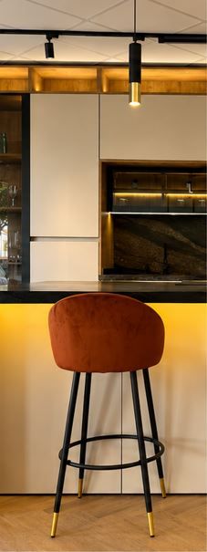 Taburete de bar color óxido en una cocina moderna con encimera de madera clara y patas de metal negro.