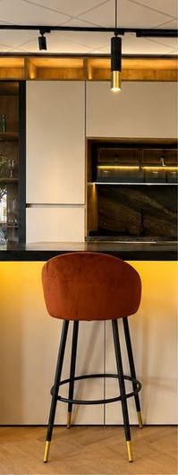 Taburete de bar color óxido en una cocina moderna con encimera de madera clara y patas de metal negro.