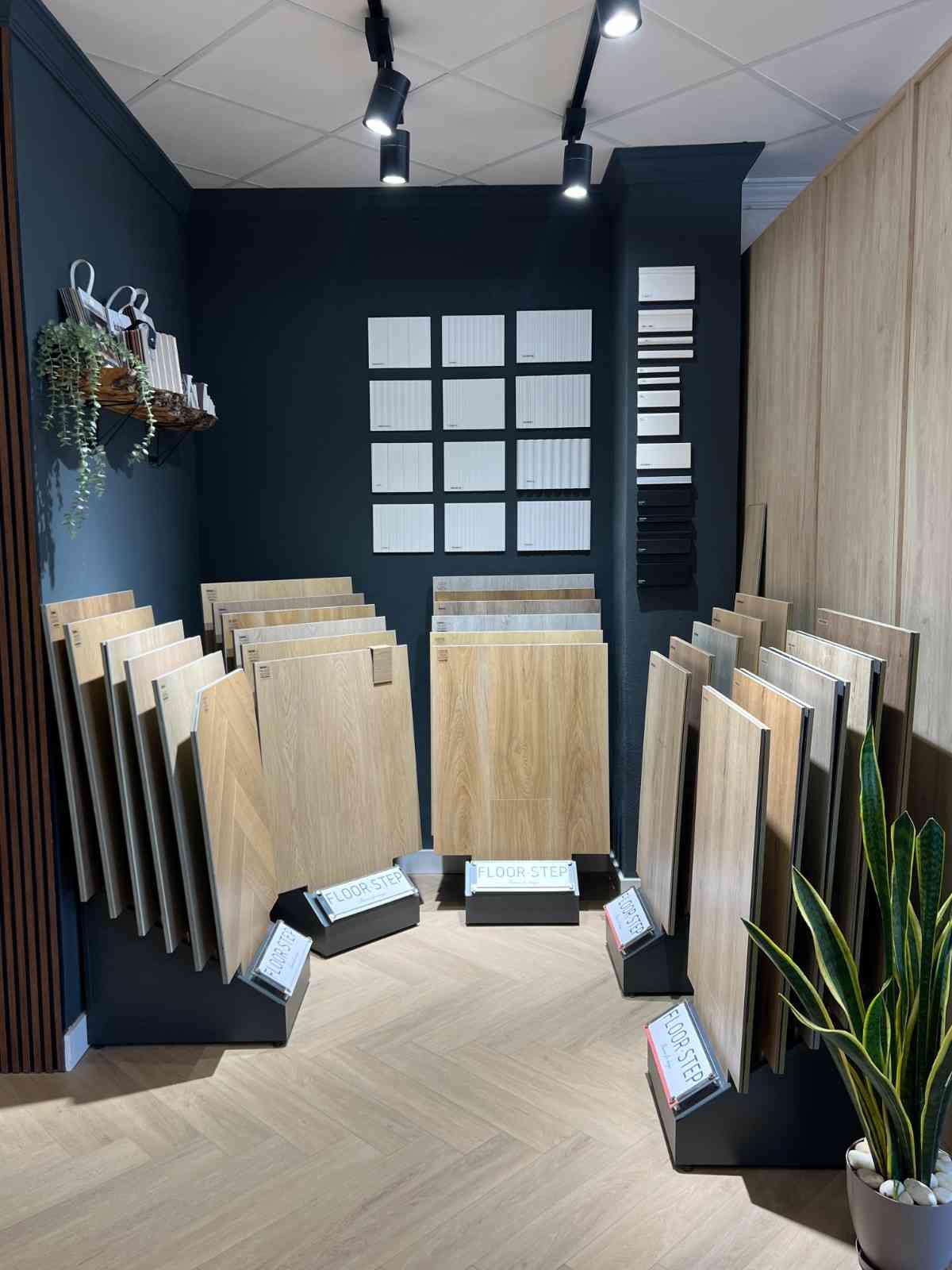 Sala de exposición de suelos con muestras expuestas en paredes y soportes en un elegante interior de madera y negro.