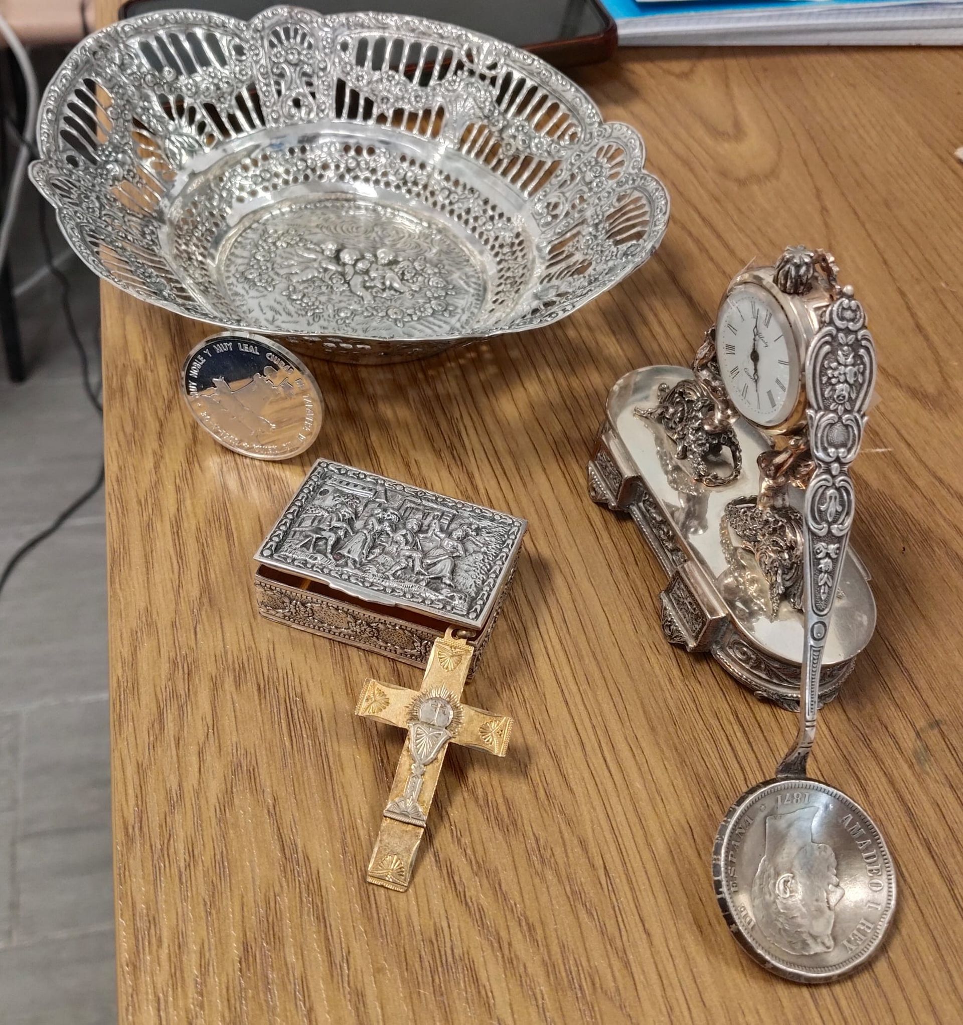 Un juego de joyas de plata sobre una mesa de madera junto a un cuenco decorativo de plata.