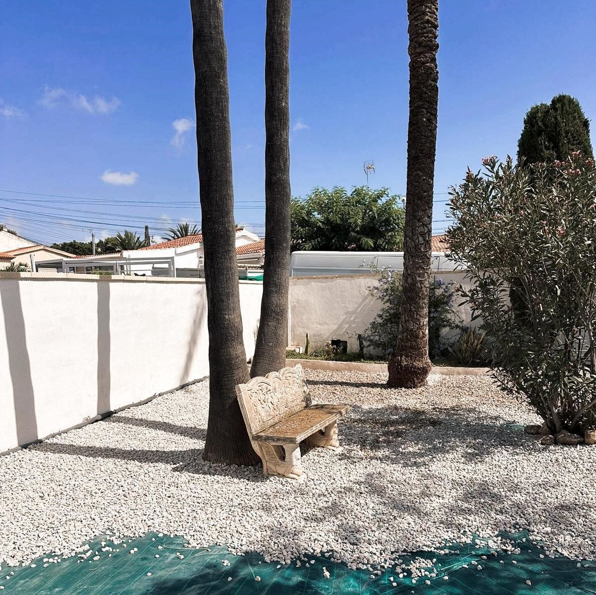 Un banco se encuentra en una zona de grava junto a una piscina.
