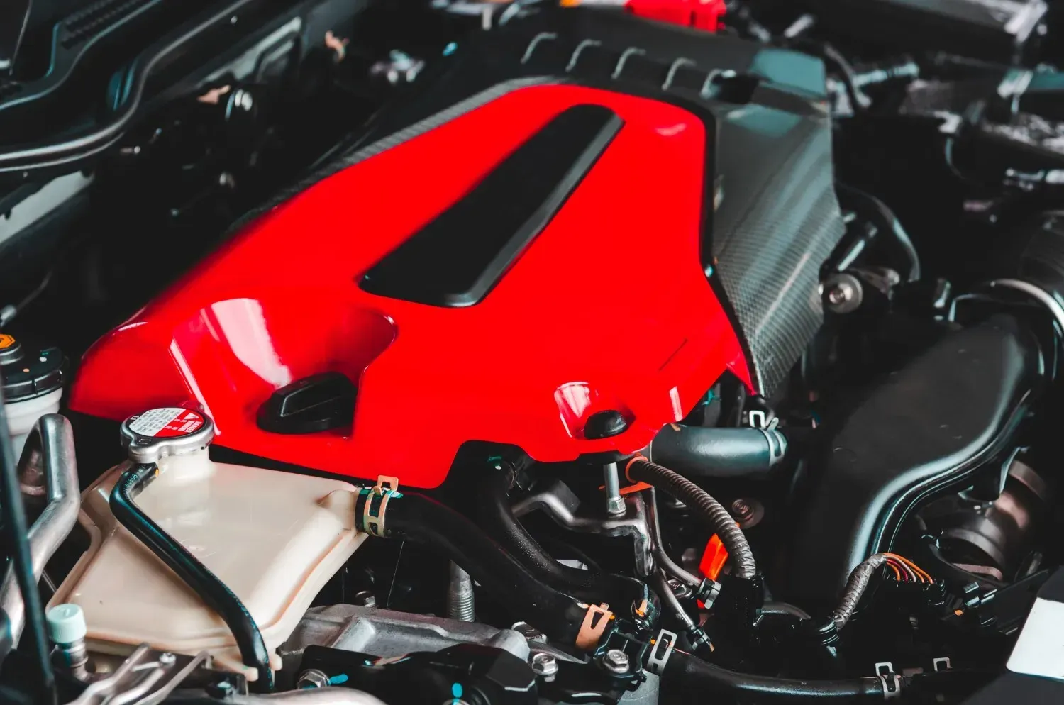 Primer plano de una cubierta de motor de coche de color rojo brillante dentro del compartimento del motor de un vehículo.