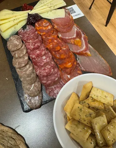 Tabla de embutidos con fiambres, queso, mermelada y galletas.
