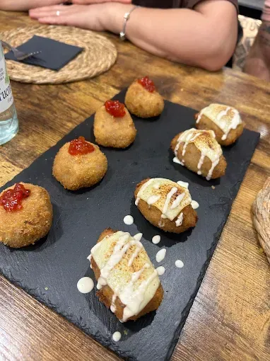 Plato de aperitivos fritos, redondos y oblongos sobre una mesa de madera.
