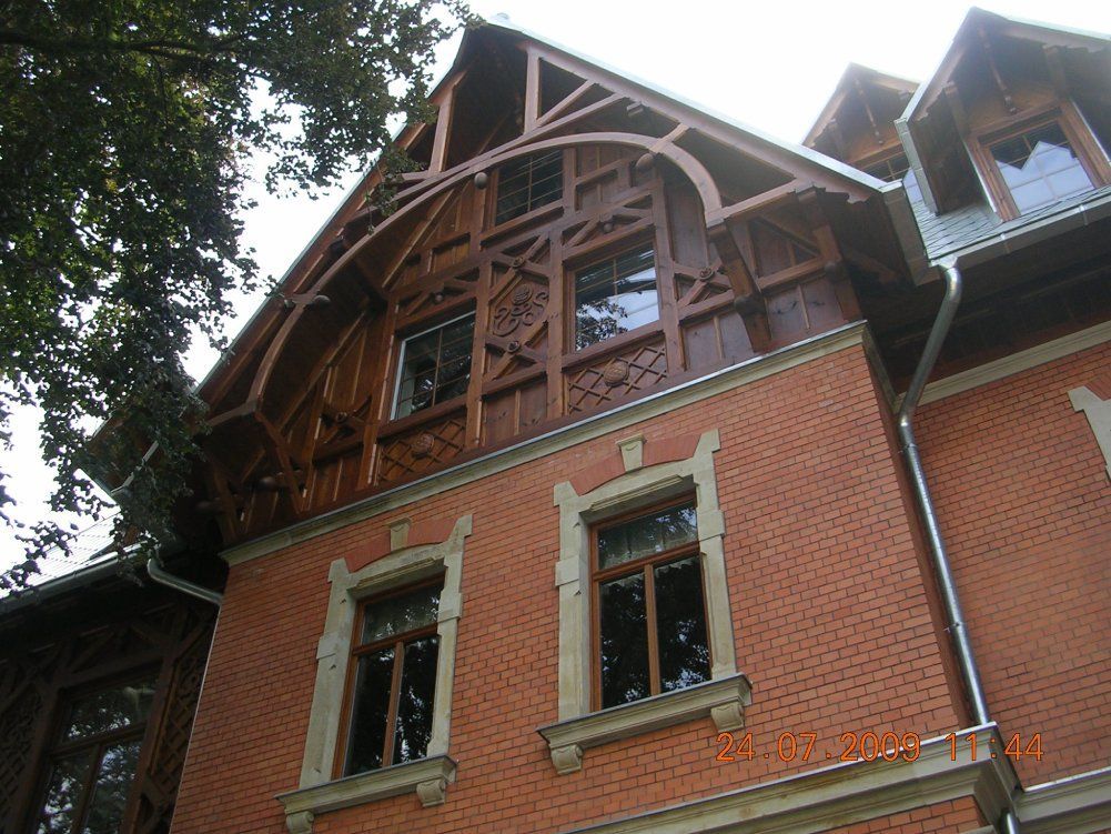Ein rotes Backsteingebäude mit weißen Steinfensterrahmen und einem reich verzierten, braunen Fachwerkgiebel unter einem steilen Dach.