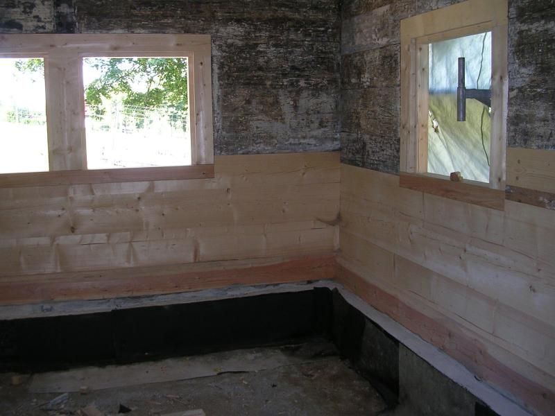 Innenecke eines rustikalen Zimmers, in der helle Holzvertäfelungen an unfertigen Steinwänden angebracht werden.