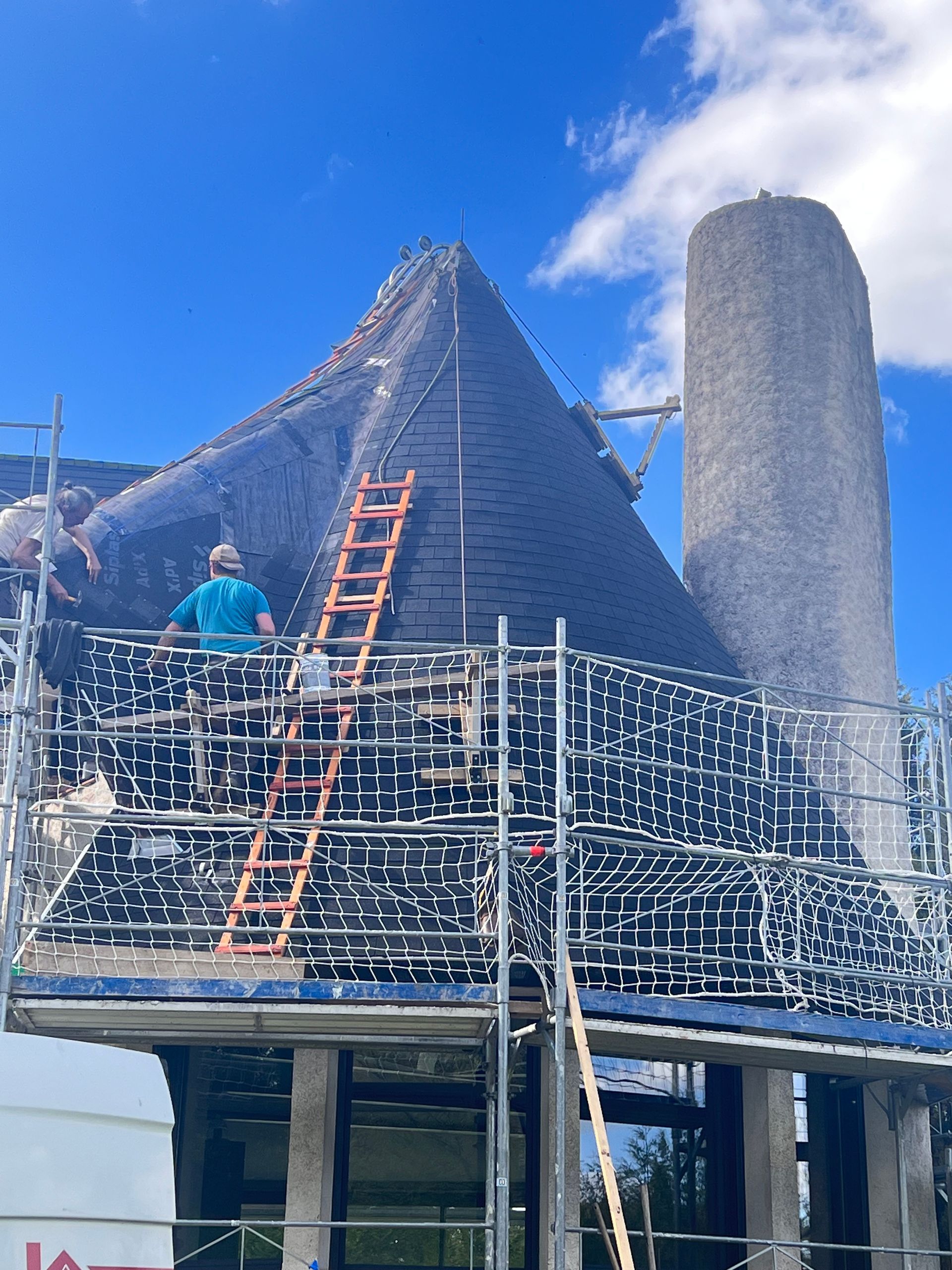 Couvreurs réalisant le remplacement d'ardoises sur un toit