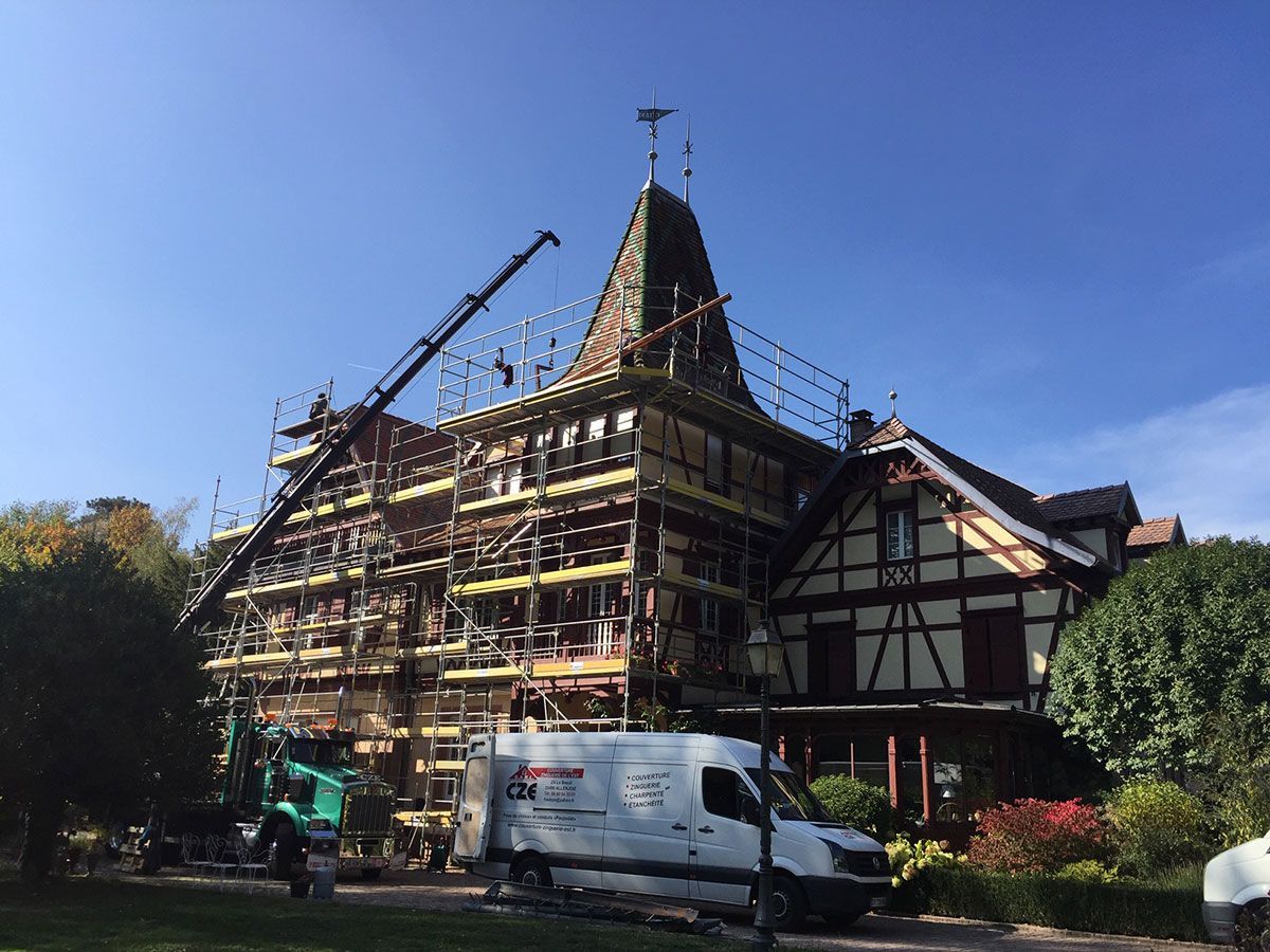 Rénovation de la toiture d'une vieille maison à colombages avec un échafaudage et un camion-grue