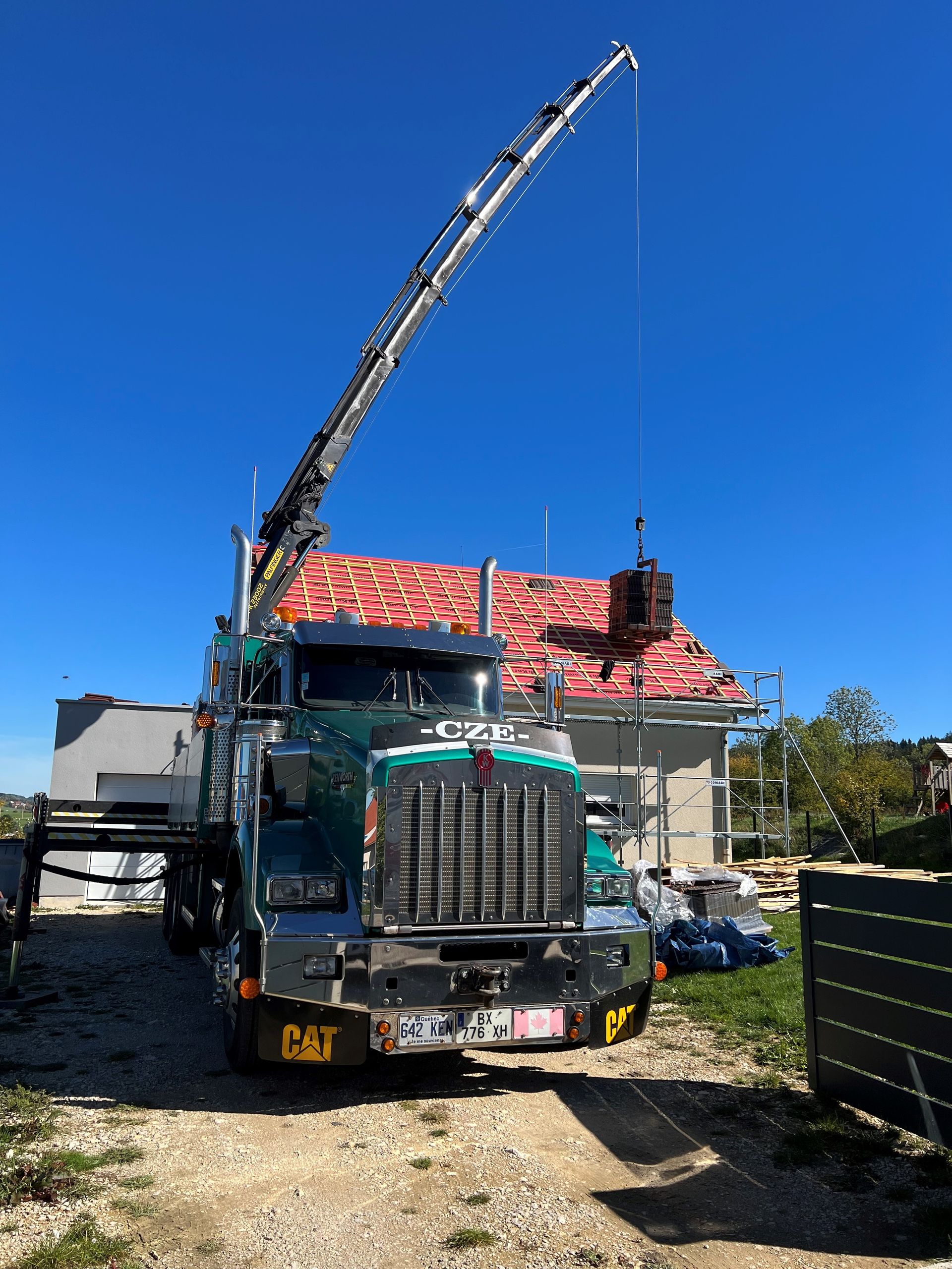 Camion vu d'en face, garé devant une maison à la couverture en rénovation