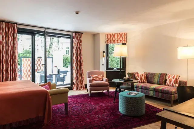 Ein Wohnzimmer mit Sofa, Stühlen, Ottomane, Tisch und Fenster.